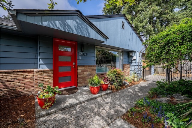 doorway to property featuring fence and stone siding