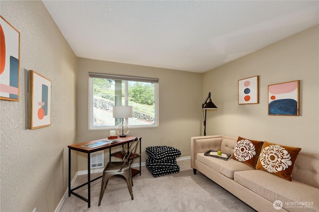 living area with carpet floors, a textured wall, and baseboards