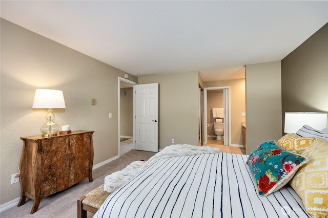 bedroom with baseboards, light carpet, and ensuite bathroom