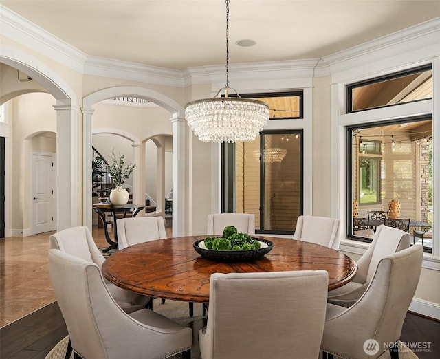 dining room with crown molding, a notable chandelier, arched walkways, and decorative columns