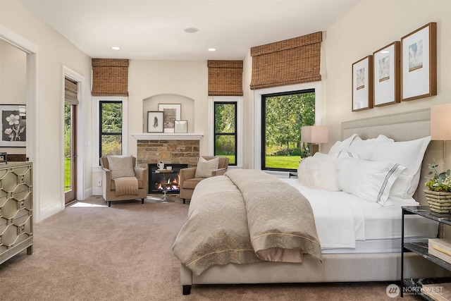 carpeted bedroom with recessed lighting, access to exterior, a stone fireplace, and baseboards