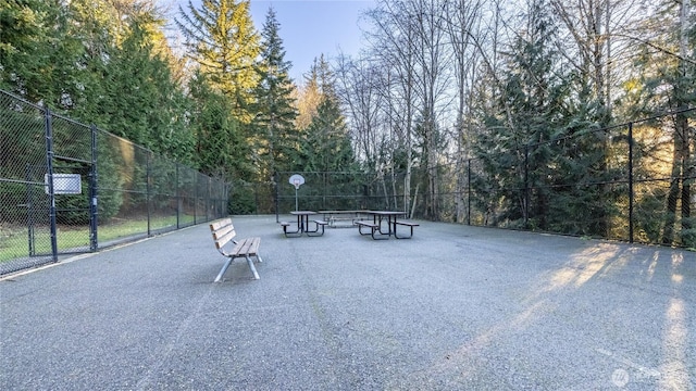view of home's community featuring community basketball court and fence