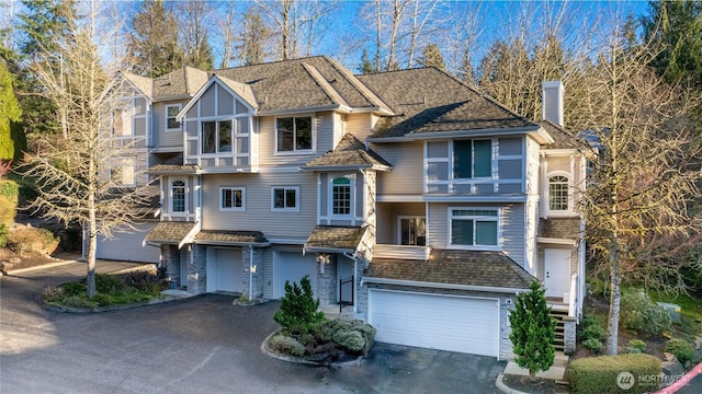 view of front of property featuring roof with shingles, an attached garage, aphalt driveway, and a chimney