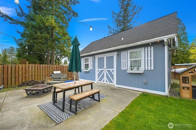 back of property with a patio, an outdoor structure, fence, and a shingled roof