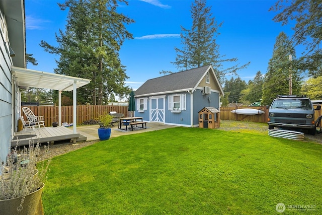 back of house with a fenced backyard, an outdoor structure, a lawn, and roof with shingles