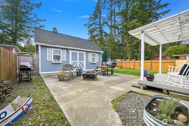 view of patio with area for grilling, a pergola, a fenced backyard, an outdoor structure, and an outdoor fire pit