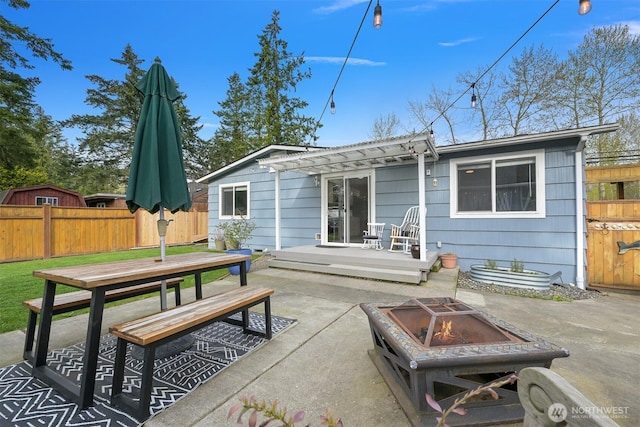 back of property featuring a patio area, outdoor dining space, fence, and a fire pit