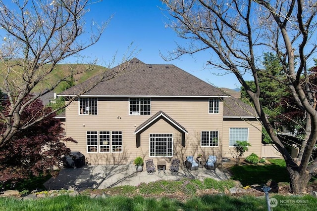 back of property with a patio area and roof with shingles