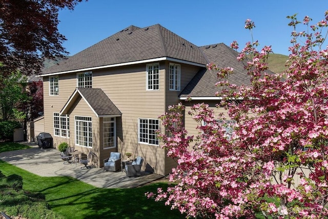 back of house with a patio area and roof with shingles