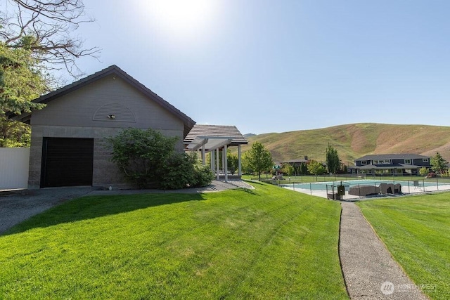 view of side of property featuring a mountain view, an outdoor pool, a garage, and driveway