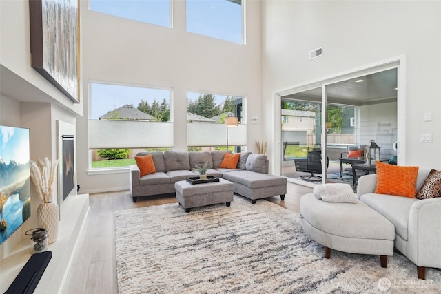 living area featuring a towering ceiling, plenty of natural light, and wood finished floors