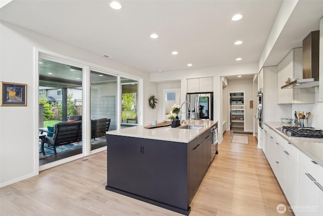 kitchen featuring modern cabinets, stainless steel gas cooktop, wall chimney range hood, a sink, and light countertops