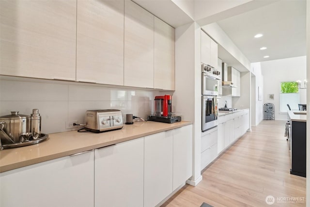 kitchen featuring modern cabinets, light wood-style floors, white cabinets, light countertops, and stainless steel double oven