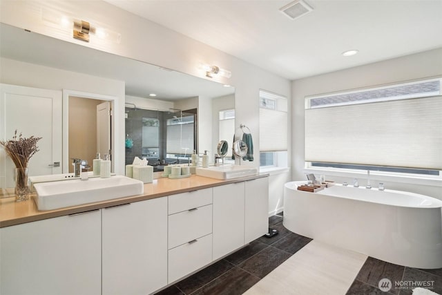 bathroom with a shower stall, double vanity, a freestanding tub, and recessed lighting