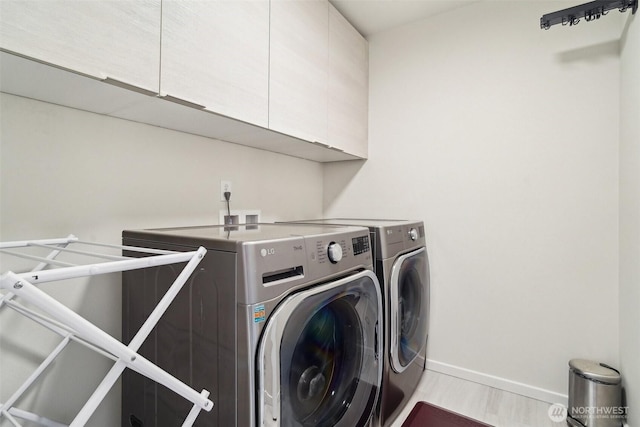 washroom with washer and clothes dryer, cabinet space, and baseboards
