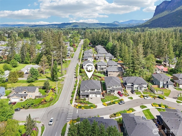 aerial perspective of suburban area featuring a forest and a mountainous background