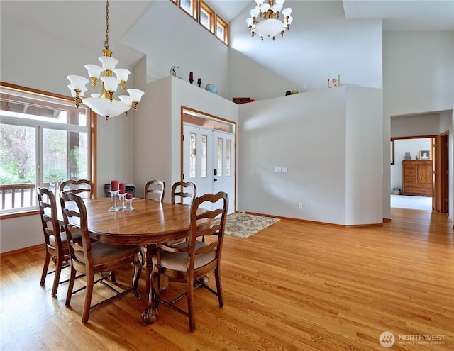 dining room featuring a high ceiling, a chandelier, and light wood-style floors