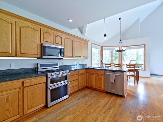 kitchen featuring stainless steel appliances, a peninsula, light wood-style floors, and hanging light fixtures