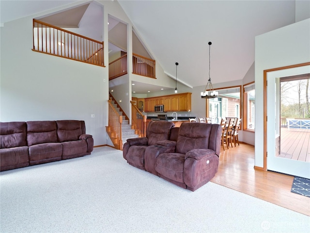 living area with light carpet, high vaulted ceiling, plenty of natural light, and stairway