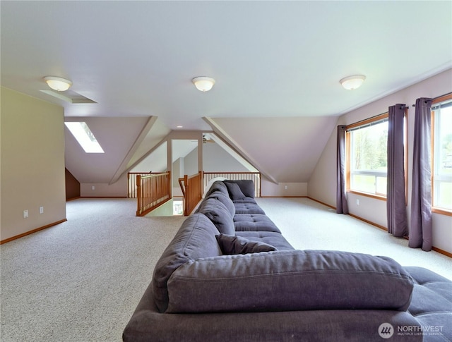 carpeted living area featuring baseboards and lofted ceiling with skylight