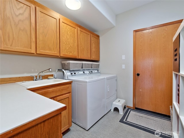 clothes washing area with washer and clothes dryer, a sink, and cabinet space
