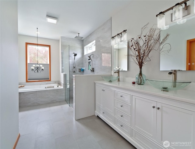 full bathroom with a tile shower, a bath, double vanity, and a sink