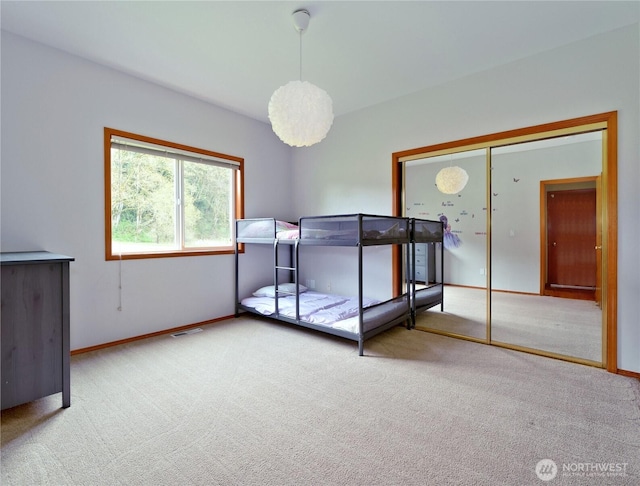 bedroom featuring a closet, carpet flooring, baseboards, and visible vents