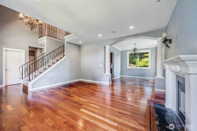 36984 Aspen Way NE, Hansville, WA 98340 - unfurnished living room featuring a chandelier, arched walkways, wood finished floors, a glass covered fireplace, and baseboards