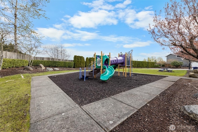 communal playground featuring fence and a lawn