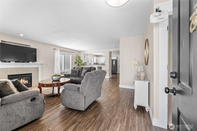 living area with a tiled fireplace, dark wood-style floors, and baseboards