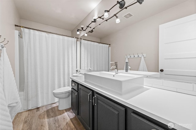 full bath with shower / bath combo, visible vents, toilet, vanity, and wood finished floors