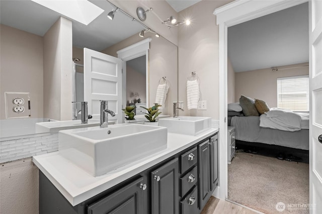 ensuite bathroom with a sink, ensuite bathroom, rail lighting, and double vanity