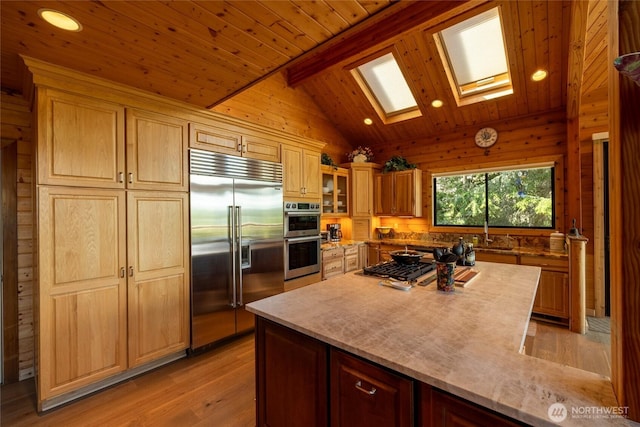 121 Marine Dr, Blakely Island, WA 98222 - kitchen featuring vaulted ceiling with skylight, light wood-style floors, wood ceiling, appliances with stainless steel finishes, and wood walls