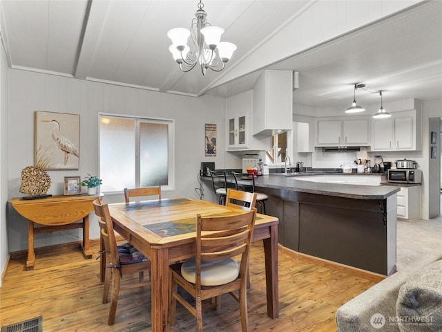 dining area with a notable chandelier, visible vents, and light wood-style flooring