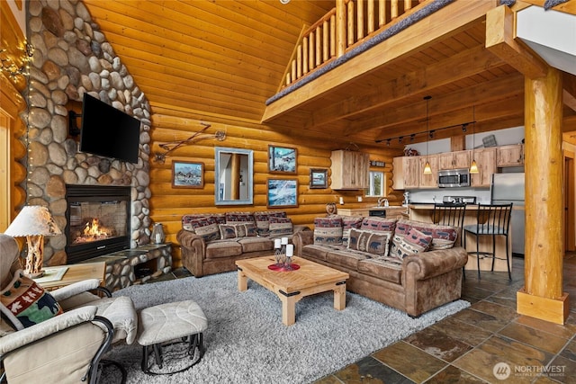 living room featuring wooden ceiling, stone tile flooring, a stone fireplace, rustic walls, and vaulted ceiling