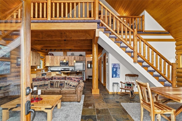 living room featuring a towering ceiling, stone finish flooring, wood ceiling, stairs, and baseboards
