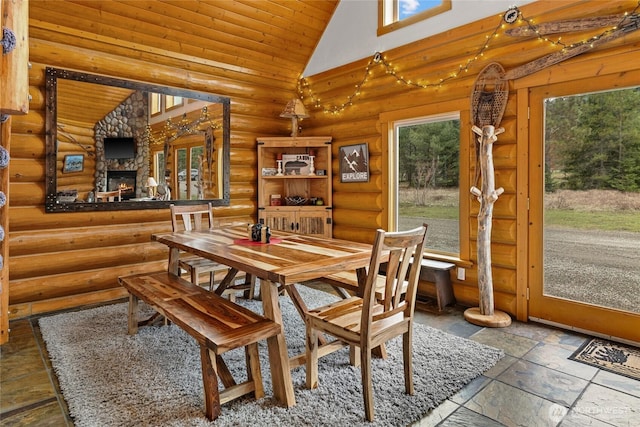 dining space with high vaulted ceiling, a fireplace, stone tile floors, wood ceiling, and log walls