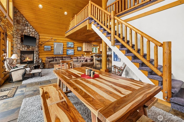 dining area featuring rustic walls, a fireplace, wood ceiling, recessed lighting, and stairway