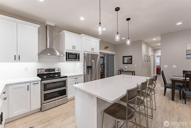 6321 Pony Pl, Maple Falls, WA 98266 - kitchen featuring wall chimney range hood, a kitchen island, white cabinetry, and appliances with stainless steel finishes