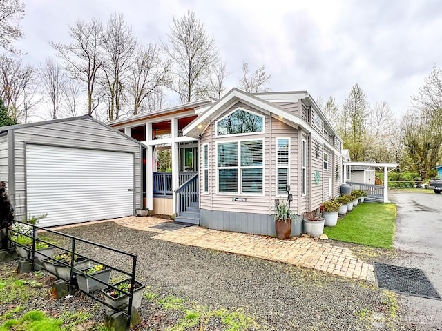 view of front facade with driveway, a detached garage, and an outdoor structure