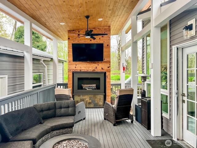 deck with an outdoor living space with a fireplace and a ceiling fan