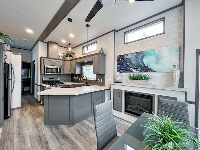 kitchen with a sink, light countertops, appliances with stainless steel finishes, gray cabinets, and decorative backsplash