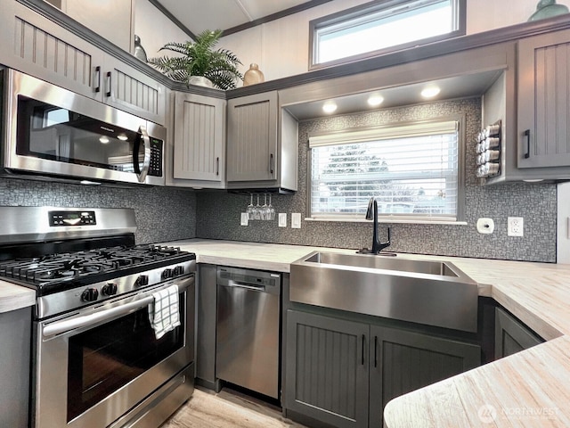 kitchen with gray cabinetry, a sink, and stainless steel appliances