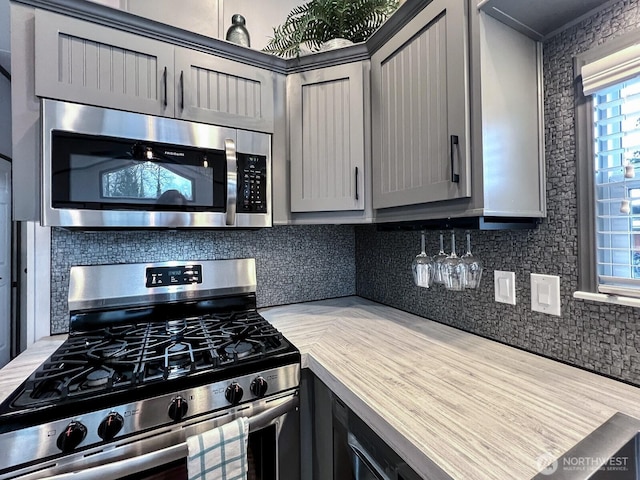 kitchen featuring gray cabinets, light countertops, backsplash, and stainless steel appliances