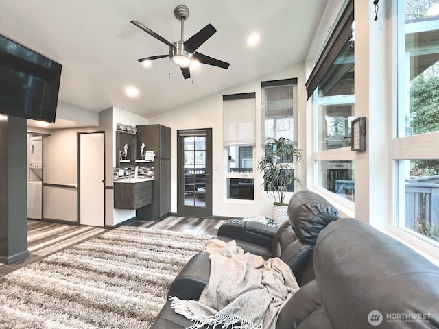 living room featuring a wealth of natural light, light wood-type flooring, ceiling fan, and vaulted ceiling