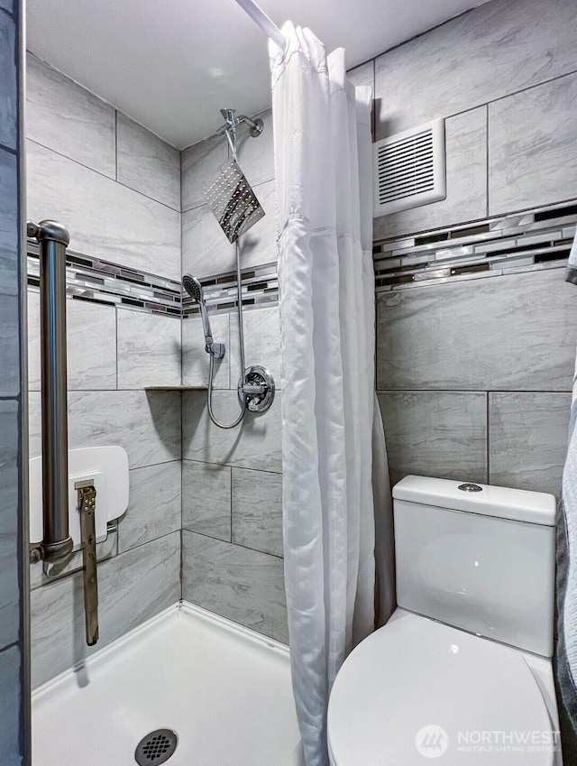 bathroom with a shower stall, visible vents, and toilet