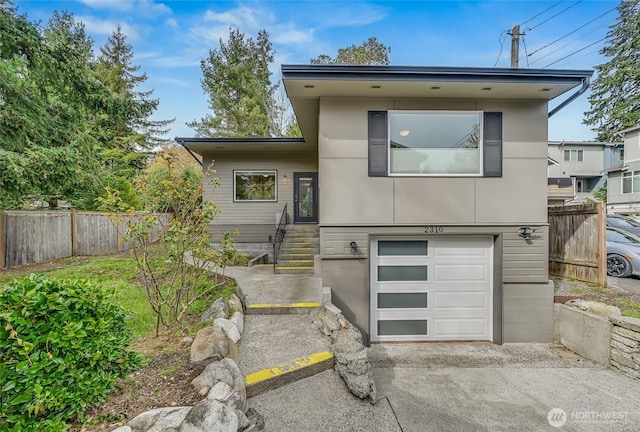 view of front of home with fence, a garage, and concrete driveway