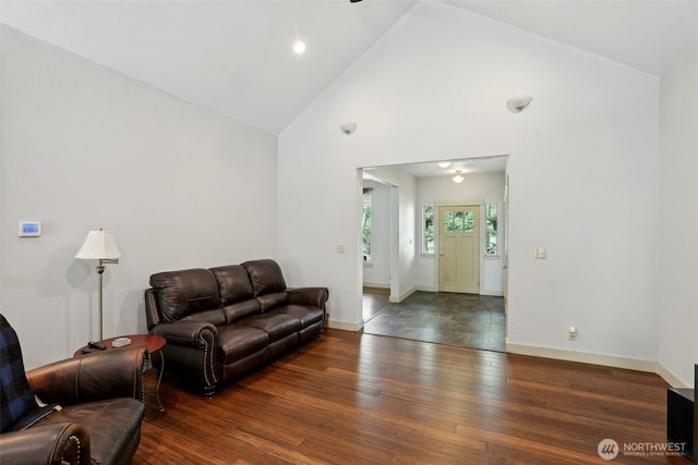 living room featuring high vaulted ceiling, baseboards, and wood finished floors