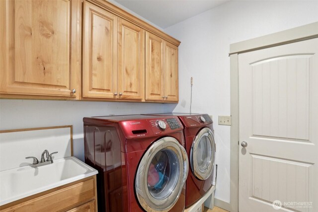 clothes washing area with cabinet space, separate washer and dryer, and a sink