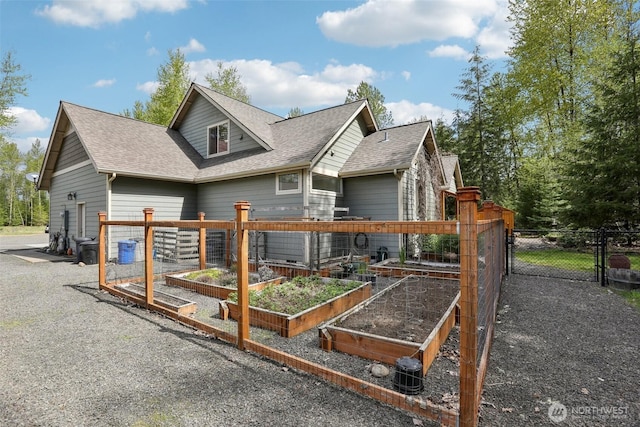 exterior space with a gate, a garden, fence, and a shingled roof